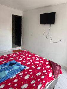 a bedroom with a bed with a red blanket with flowers at Hotel São João in Itaituba