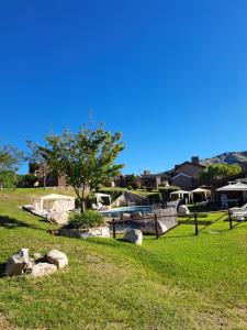 a park with rocks and a tree in the grass at Vista Bella Cabañas in La Falda
