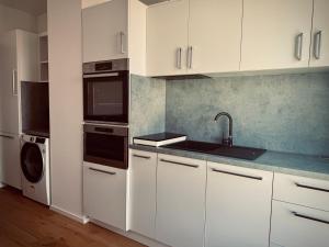 a kitchen with white cabinets and a sink and a microwave at Pekanda apartment in Brno +11 photos