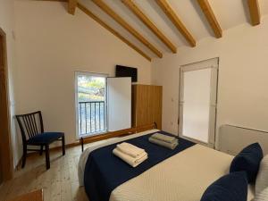 a bedroom with a bed and a chair and a window at Quinta do Carvalho Cerquinho in Louriceiras de Baixo +33 photos