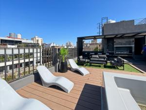a rooftop deck with white chairs and tables on a building at Ayres Suites Cochabamba in Buenos Aires