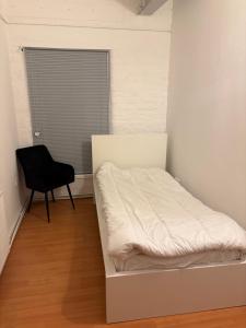 a white bed in a room with a black chair at 3 Bed Luxury Contractors Apartment, Free Parking, City Centre, Fast WiFi by Opulent Stays in Derby