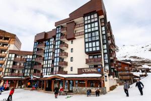 a large building with people in the snow in front of it at Résidence Eskival - ESKIVAL APPARTEMENT 35M² 4 PERS CENTRE STATION ACCES DIRECT SUR LES PISTES MAE-7717 in Val Thorens