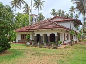 a house in a yard with palm trees in the background at Naolina Beach Villa in Weligama