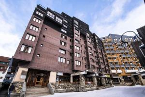 a tall brick building in a city at Résidence Arcelle - VAL THORENS location: studio cabine en plein centre de la station MAE-9104 in Val Thorens