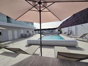 a patio with an umbrella and chairs and a pool at Lagoon Suits in San Borondón
