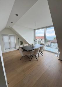 a dining room with a table and chairs and large windows at Tolle Wohnung mit Seeblick! in Rorschach