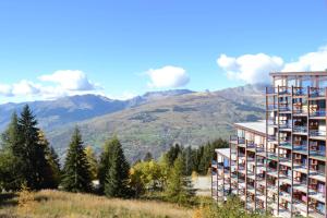 a building on a hill with mountains in the background at Résidence Armoise - Studio 3 personnes à Arc 1800 en centre station, proche des pistes et des commerces, dans le village des Villards MAE-1847 in Arc 1800
