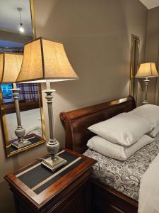 a bed with a table with a lamp and a mirror at Red Robin Cottage in Castlewellan