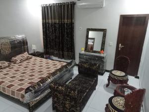 een slaapkamer met een bed, een spiegel en stoelen bij Ryazm Guest house in Rawalpindi
