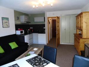 un soggiorno con un divano nero e una cucina di Résidence Chamois - Studio pour 4 Personnes MAE-9324 a Modane