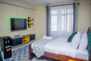 Un dormitorio con una cama y un televisor de pantalla plana. en Pink Lounge Suites, en Nairobi