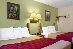 a hotel room with two beds with red sheets at Econo Lodge, Downtown Custer Near Custer State Park and Mt Rushmore in Custer