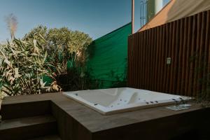 戈亚斯州上帕莱索Vila Astra - jacuzzi gigante, telão 120 polegadas, próximo de tudo的浴室里有一个大浴缸，墙上有绿色植物