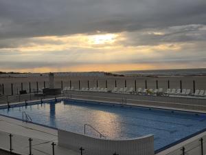 a swimming pool next to a beach with the ocean at Oostduinkerke View in Oostduinkerke