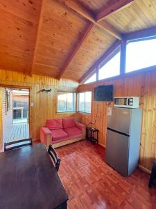 a living room with a red couch and a refrigerator at Cáhuil Cabañas Central in Cáhuil