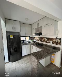 a kitchen with white cabinets and a black refrigerator at Apartamento de Vacaciones con Piscinas y Jacuzzi - Perfecta para Grupos - By Molca Travel in Armenia