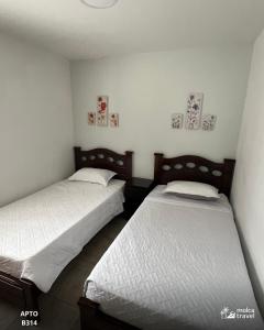 two beds in a room with white sheets at Apartamento de Vacaciones con Piscinas y Jacuzzi - Perfecta para Grupos - By Molca Travel in Armenia