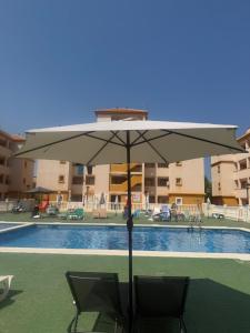 a umbrella and two chairs in front of a pool at Estrella in Mar de Cristal