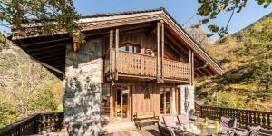 a log cabin with a balcony and a table at Résidence Hameau Des Rochers - Chalets pour 14 Personnes MAE-3284 in Champagny-en-Vanoise