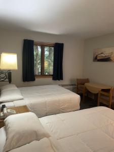 1 dormitorio con 3 camas, mesa y ventana en Square Rigger Lodge, en Jacksonport