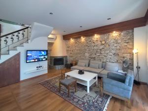 Zografia cottage في Lámpou Mýloi: غرفة معيشة مع أريكة ومدفأة