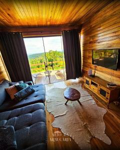 a living room with a couch and a large window at Cabana Araucária in Bom Retiro