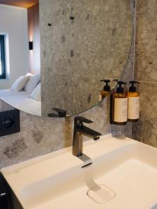 a bathroom sink with a mirror and two bottles of soap at Door9 Hasselt - Digital Hotel in Hasselt