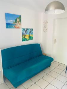 ein blaues Sofa in einem Raum mit zwei Gemälden in der Unterkunft La Maison du Bonheur & Escapade Côte Bleue in Martigues