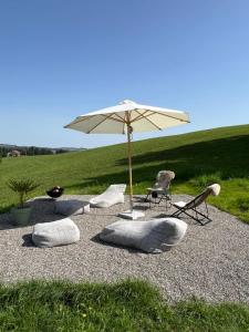 a group of chairs and an umbrella on a gravel area at Allgäu Cottage - traumhafter Blick in die Schweizer Berge in Weiler-Simmerberg