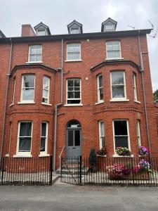 a red brick house with white windows and a gate at Rock Park Penthouse in Llandrindod Wells