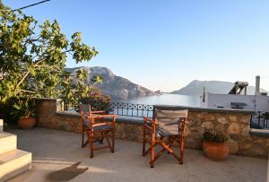a patio with two chairs and a table with a view of the water at Skalia Mountain & Sea Suites in Skaliá