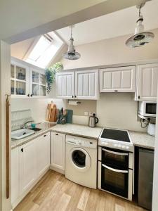 a kitchen with white cabinets and a dishwasher at Seatown Cottage - Stone's throw from beach in Lossiemouth