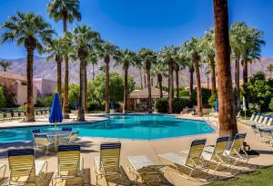 einen Pool mit Chaiselongue und Palmen in der Unterkunft Chic Downtown Bungalow in Palm Springs