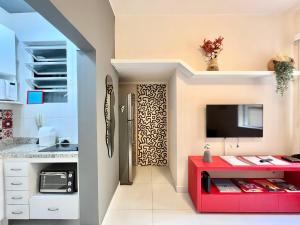 a kitchen with a red table and a tv at Apartamento pertinho da praia e do metrô in Rio de Janeiro