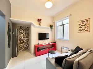 a living room with a couch and a tv on a wall at Apartamento pertinho da praia e do metrô in Rio de Janeiro +11 photos