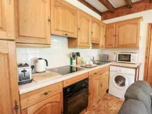 a kitchen with wooden cabinets and a washer and dryer at Royal Oak Farm Cottage in Betws-y-coed +15 photos