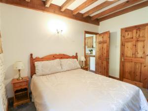 a bedroom with a large bed with a wooden headboard at Royal Oak Farm Cottage in Betws-y-coed