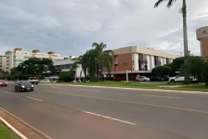 a black car driving down a city street with buildings at Lof Top perto QG,Cong ,Minist e Aerop ( N-119) in Brasilia