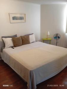 Un dormitorio con una cama grande con sábanas y almohadas blancas. en Apartamentos Isaurys, en Santiago