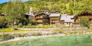 a large house next to a river with a mountain at Chalet Paradis Blanc - Chalet 4 - 129m2 - 6 chambres, 6 salles de bain MAE-2024 in Tignes