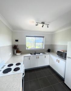 an empty kitchen with white cabinets and a sink at Sea Salt One Burgess Beach in Forster