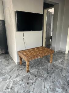 a wicker bench in a room with a flat screen tv at Inala Urban Guesthouse in Bulawayo