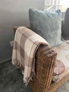 a blanket on a wicker couch with a pillow at Inala Urban Guesthouse in Bulawayo