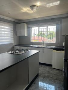 a kitchen with white cabinets and a black counter top at Inala Urban Guesthouse in Bulawayo