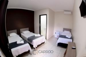 a hotel room with two beds and a mirror at Carrijo Hotel in Marília