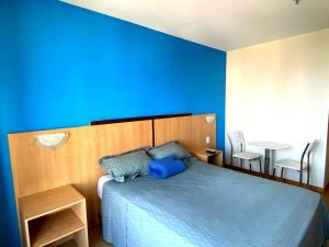 a blue bedroom with a bed and a table at Flat Particular Hotel Confort Taguatinga in Taguatinga +47 photos