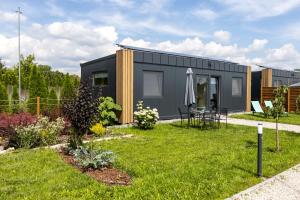 a small black house with a garden and an umbrella at Ostoja Czersk Góra Kalwaria Zamek Królowej Bony Domki całoroczne in Czersk