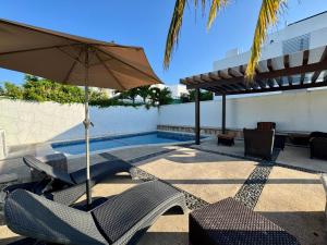 a pool with two chairs and an umbrella at Casa Bella in Playa del Carmen
