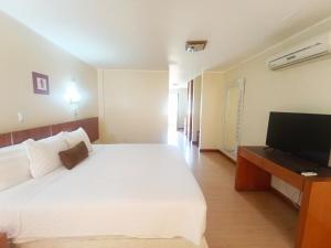 a bedroom with a large white bed and a flat screen tv at Hotel La Estancia in Cabudare